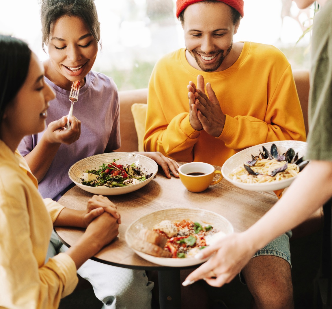 Friends sitting and eating at a small table.